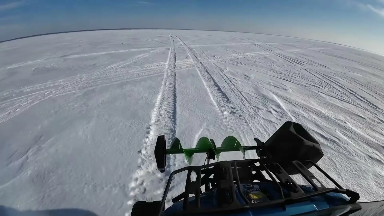 An auger and sled pulled across a wide stretch of ice.