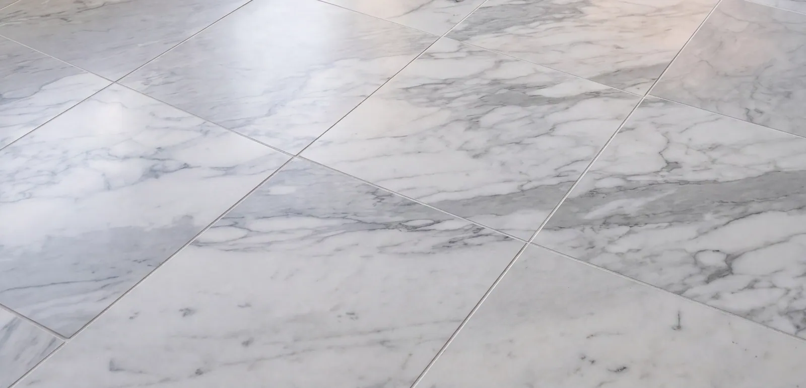 Large white veined stone floor tiles with grey veining, seen at a low angle.