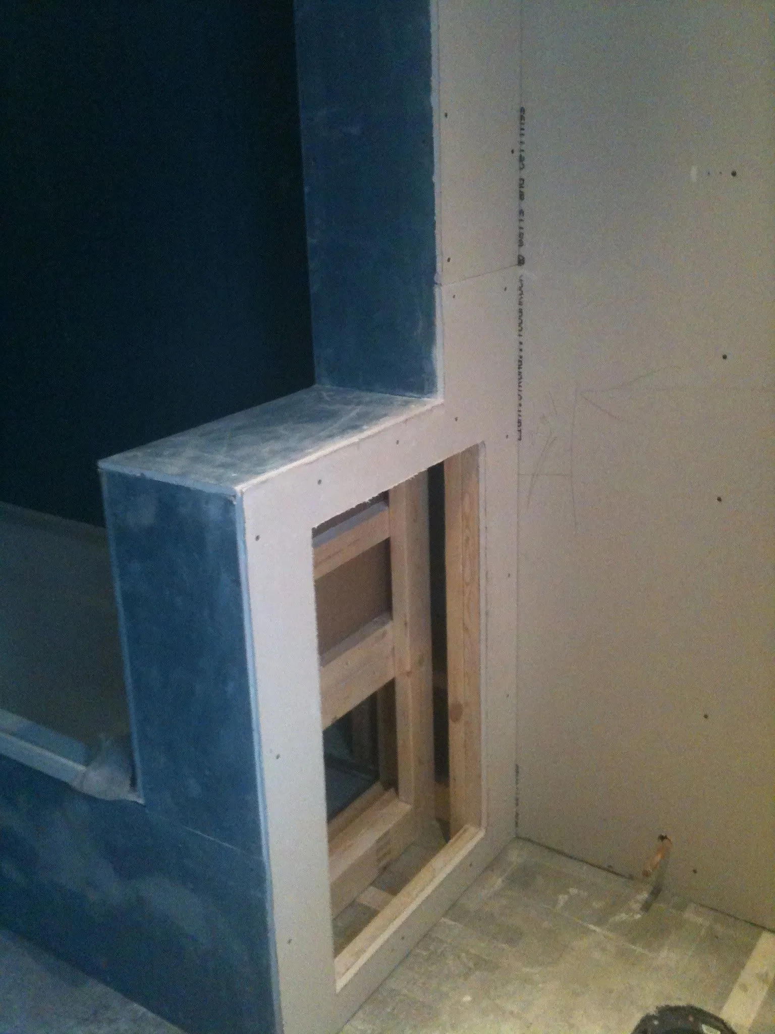 A shower wall in blue cement board with a framed niche opening.
