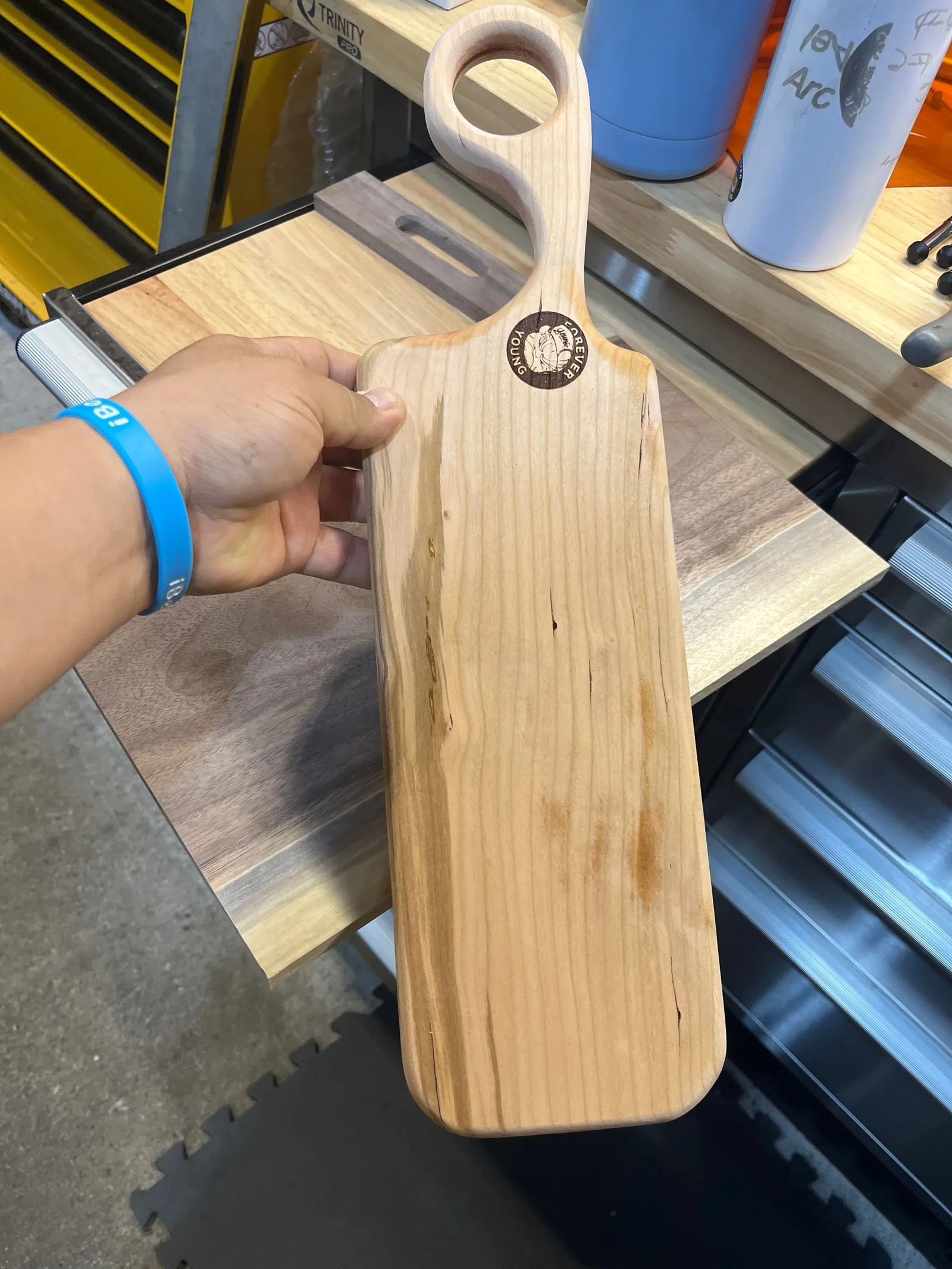 A hand holding a paddle-shaped wooden board.