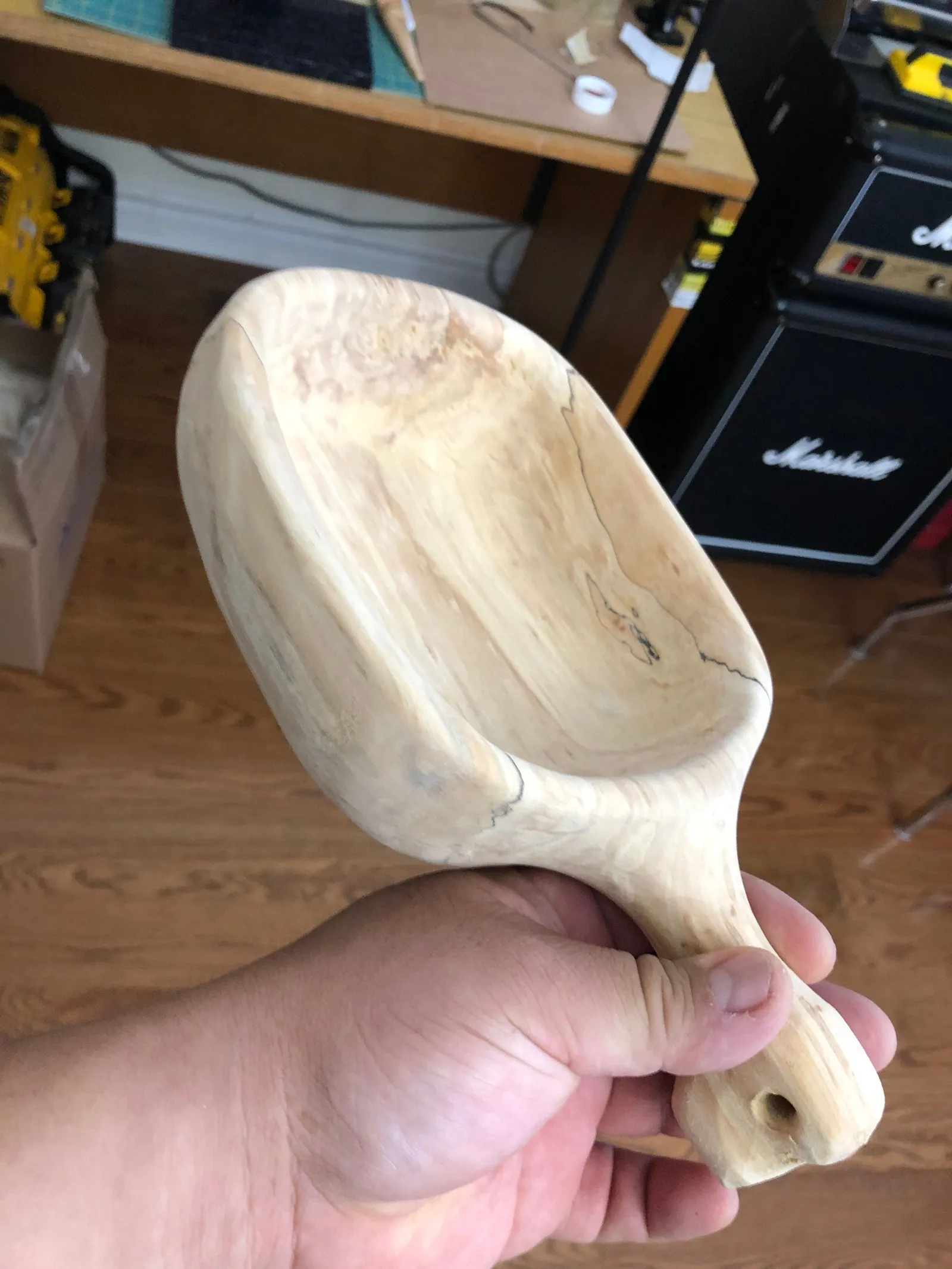 A carved wooden scoop held in a hand.